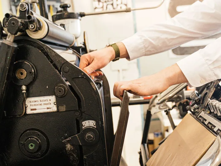 Hands adjusting the mechanisms of a printing press